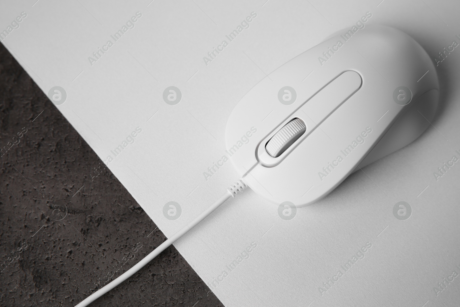 Photo of Wired mouse with mousepad on black textured table, top view
