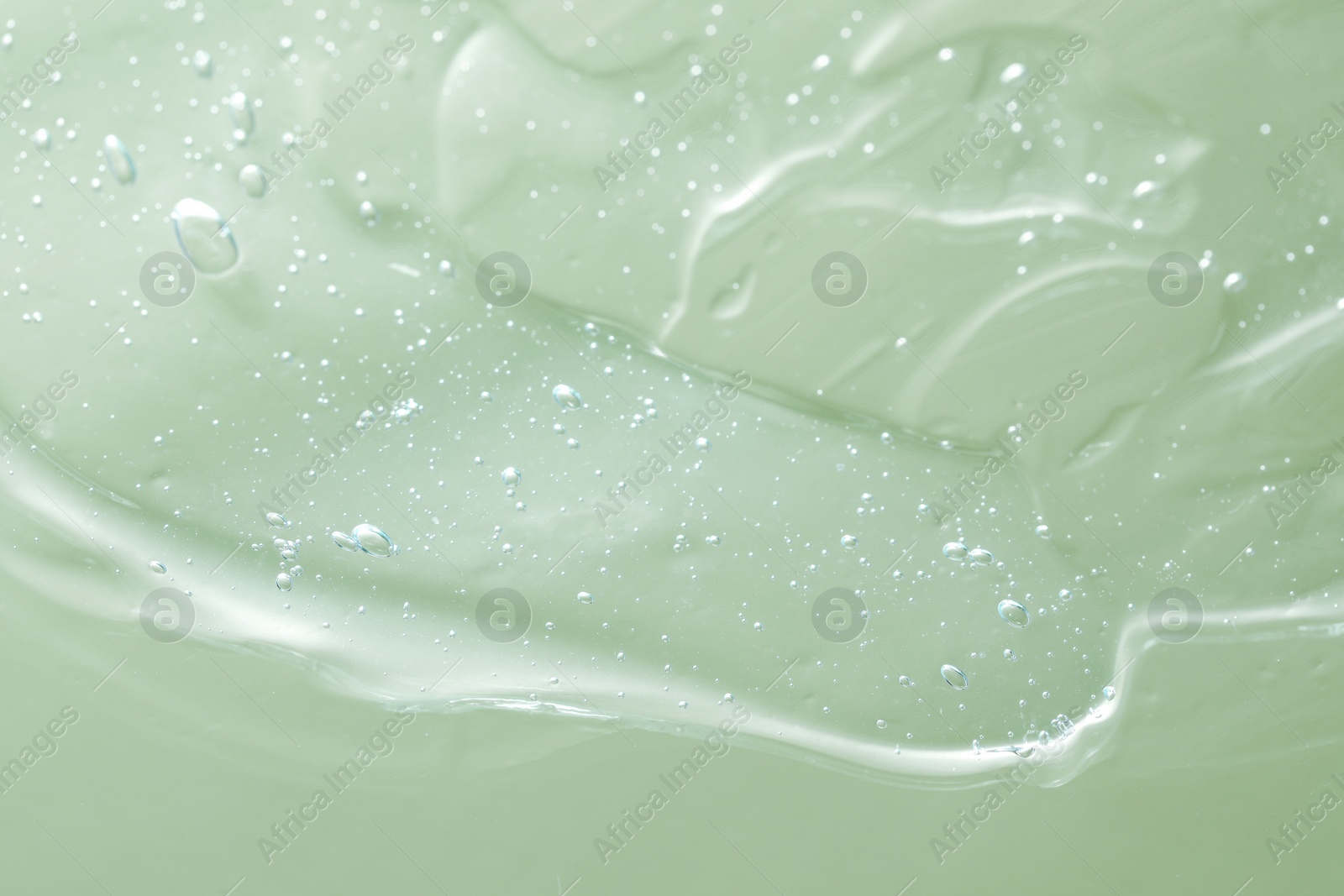 Photo of Transparent cleansing gel on green background, closeup. Cosmetic product