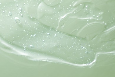 Photo of Transparent cleansing gel on green background, closeup. Cosmetic product