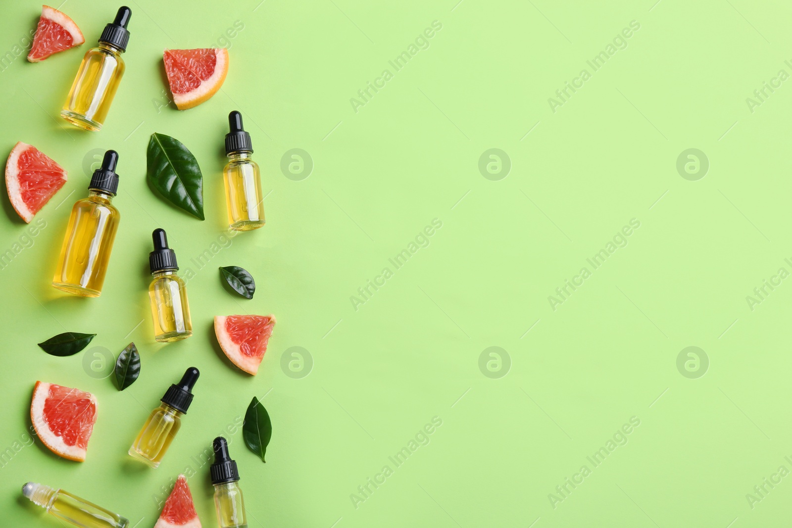 Photo of Flat lay composition with bottles of grapefruit essential oil on green background. Space for text