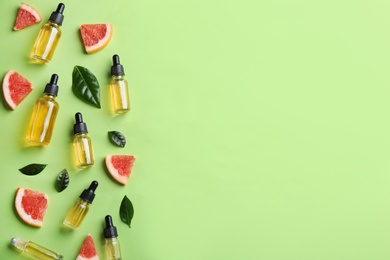Photo of Flat lay composition with bottles of grapefruit essential oil on green background. Space for text
