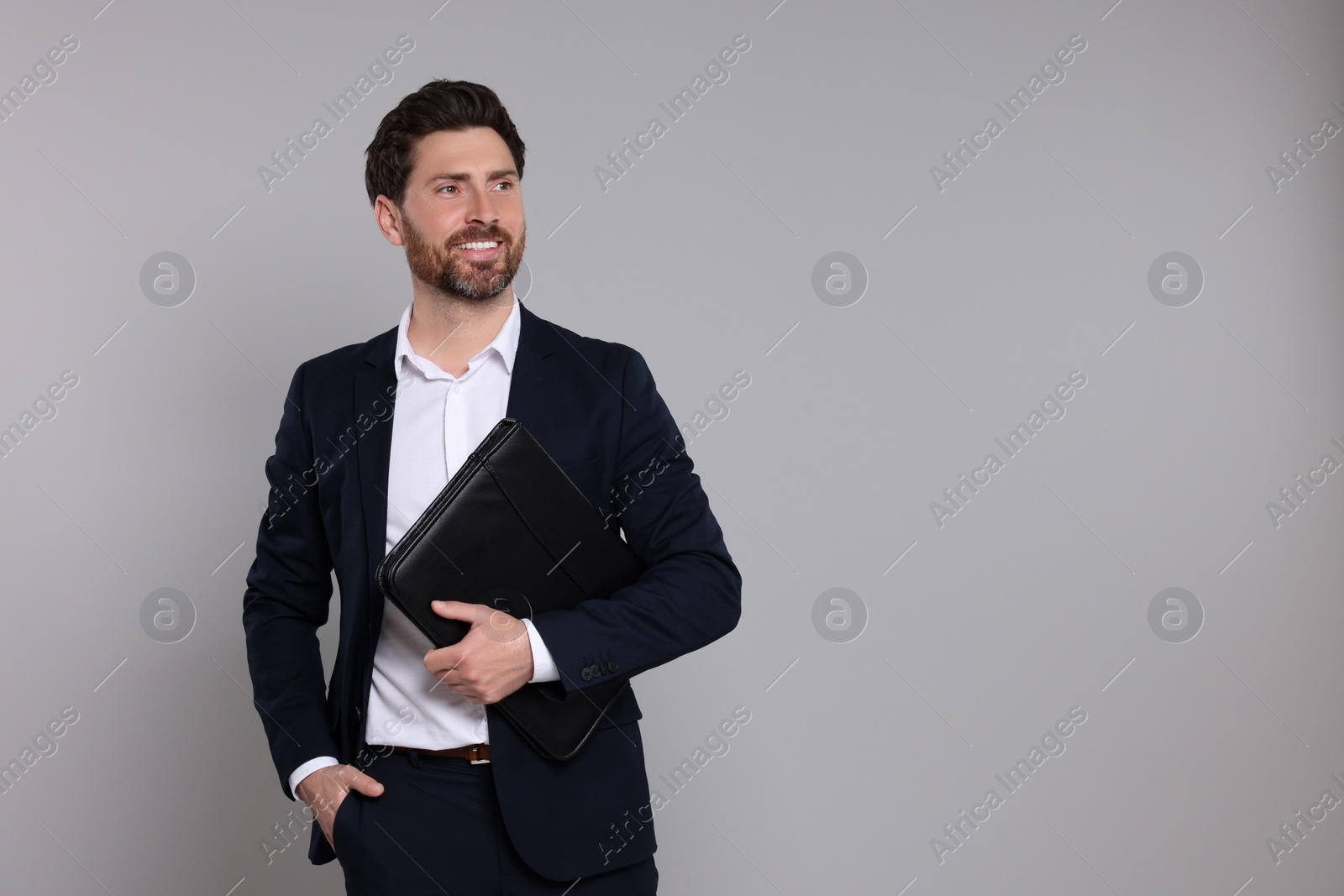 Photo of Happy real estate agent with leather portfolio on grey background. Space for text