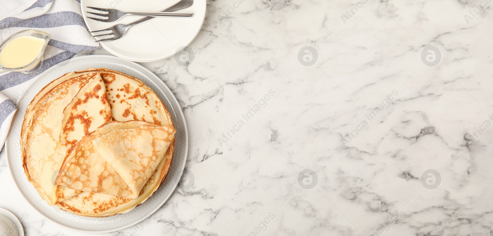 Image of Fresh thin pancakes served on white marble table, flat lay. Banner design, space for text
