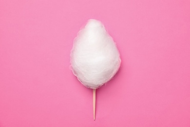 Photo of Stick with yummy cotton candy on color background, top view