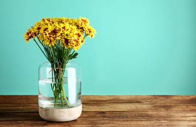 Photo of Vase with beautiful chrysanthemum flowers on wooden table. Space for text