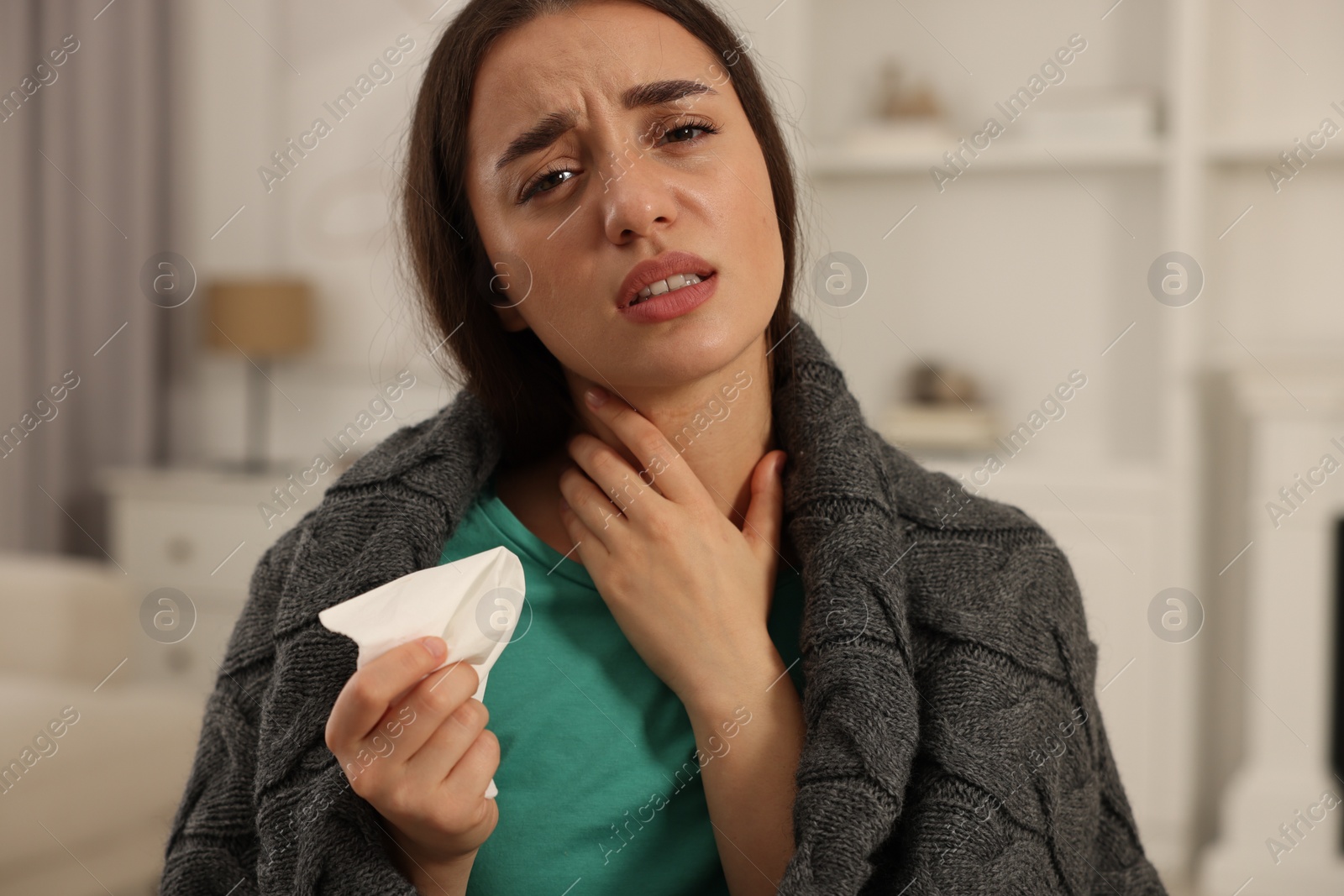 Photo of Sick woman wrapped in blanket with tissue at home. Cold symptoms