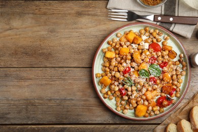 Photo of Delicious fresh chickpea salad served on wooden table, flat lay. Space for text