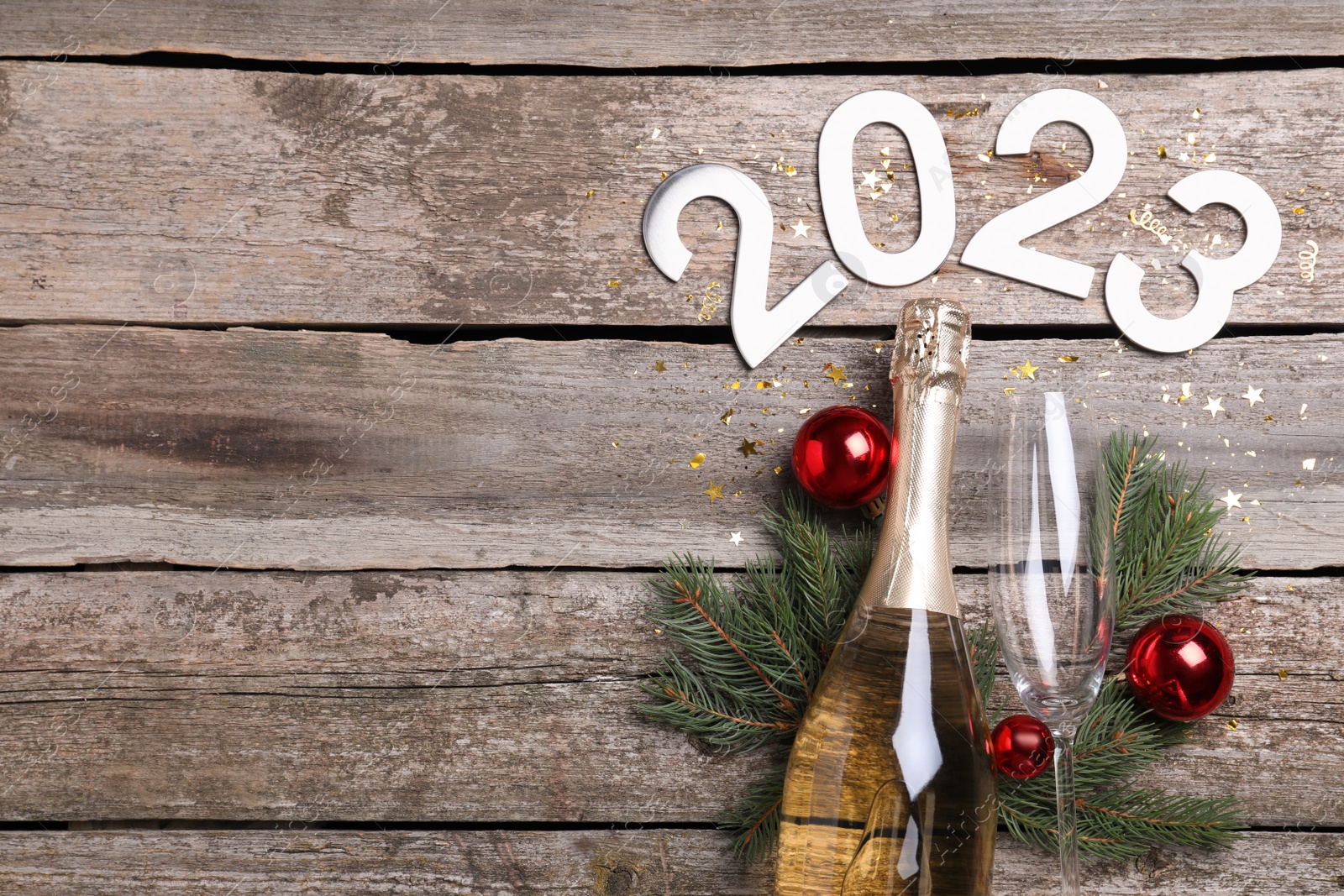 Photo of Happy New Year 2023! Flat lay composition with bottle of sparkling wine on wooden table, space for text