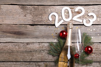 Photo of Happy New Year 2023! Flat lay composition with bottle of sparkling wine on wooden table, space for text