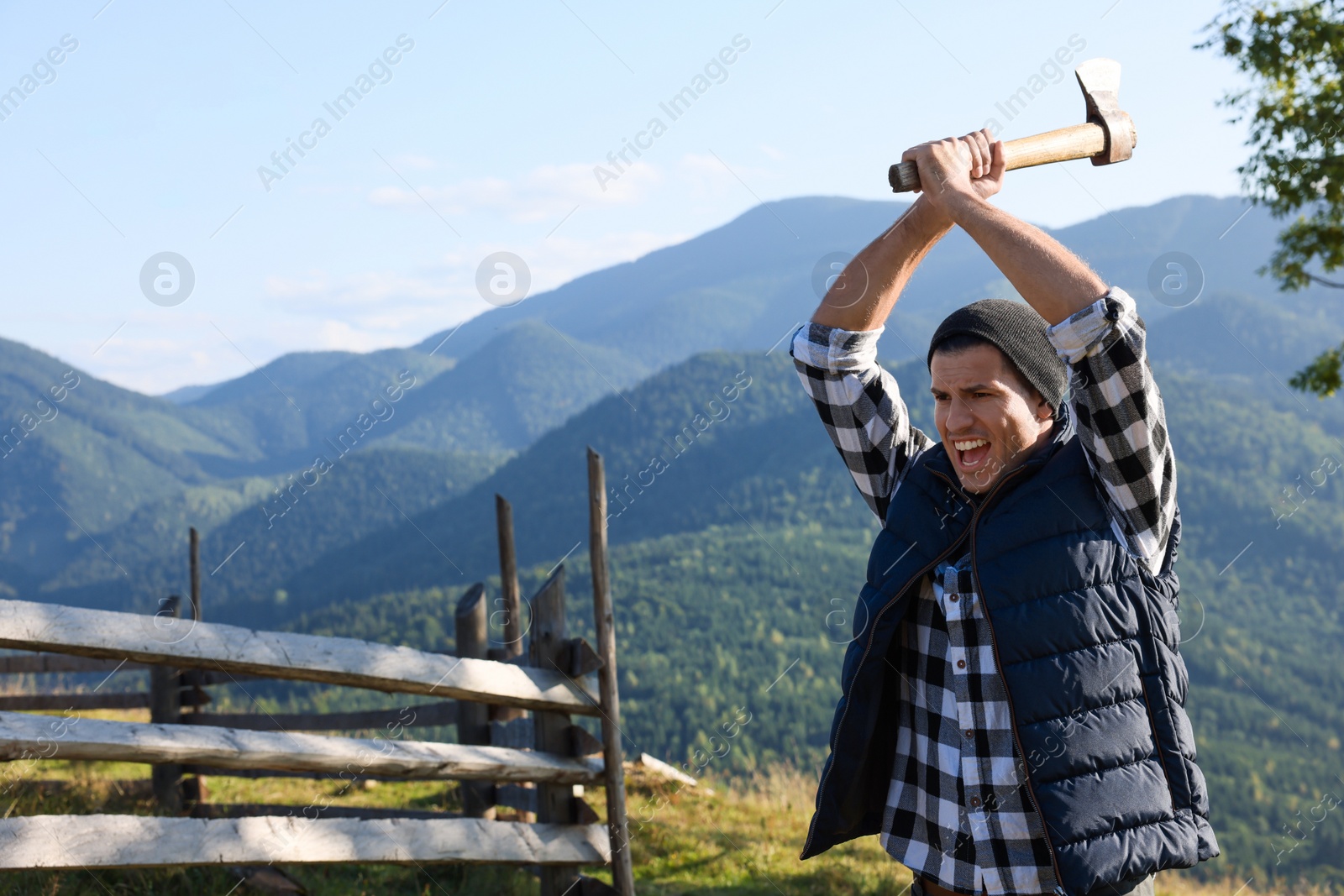 Photo of Handsome man swinging axe in mountains, space for text