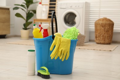 Different cleaning products and bucket on floor indoors