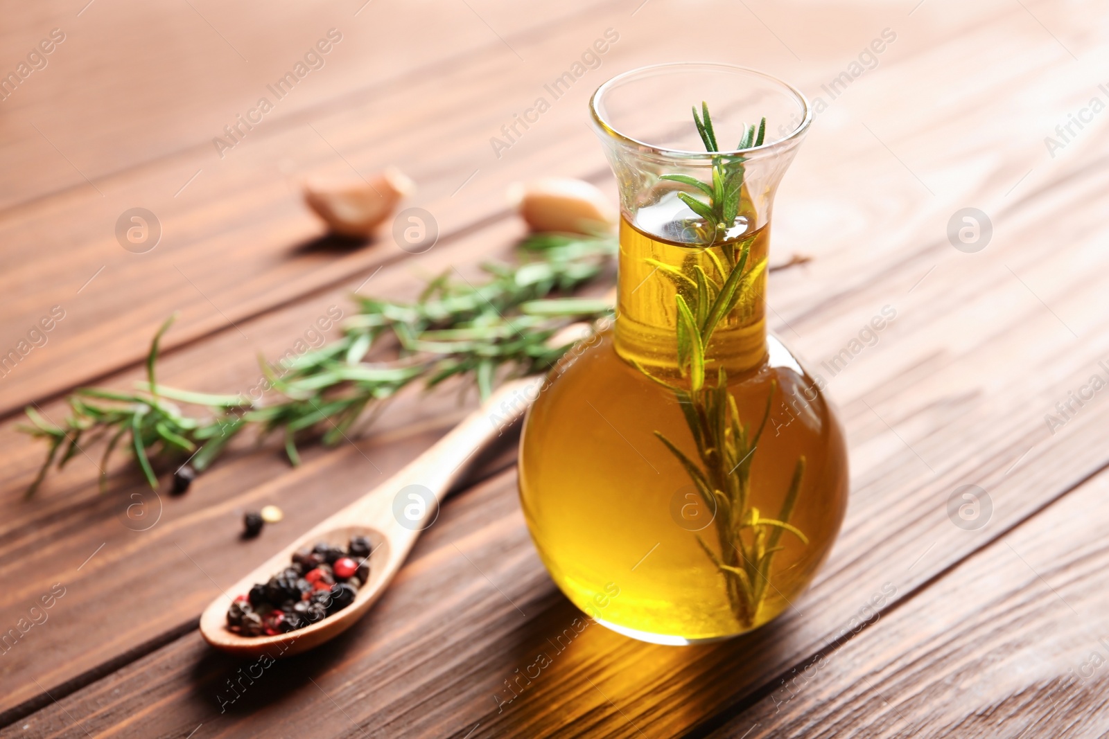 Photo of Bottle of rosemary oil with fresh twigs on wooden background