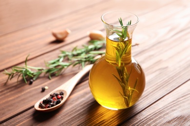 Bottle of rosemary oil with fresh twigs on wooden background