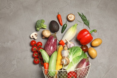 Photo of Different vegetables and metal basket on grey background, top view