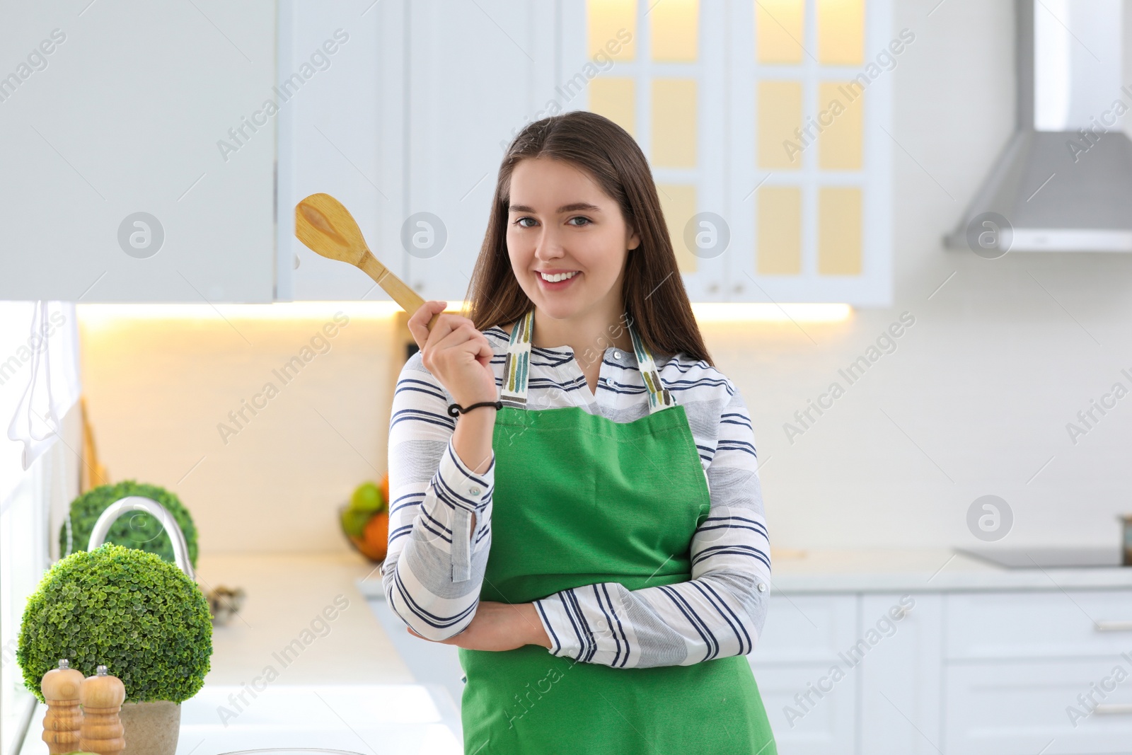 Photo of Young woman with apron and spatula in kitchen