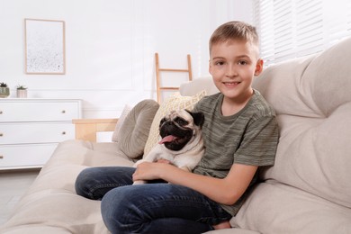 Photo of Boy with his cute pug on sofa at home. Space for text