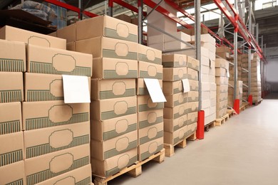 Photo of Warehouse with stacks of boxes on wooden pallets. Wholesaling