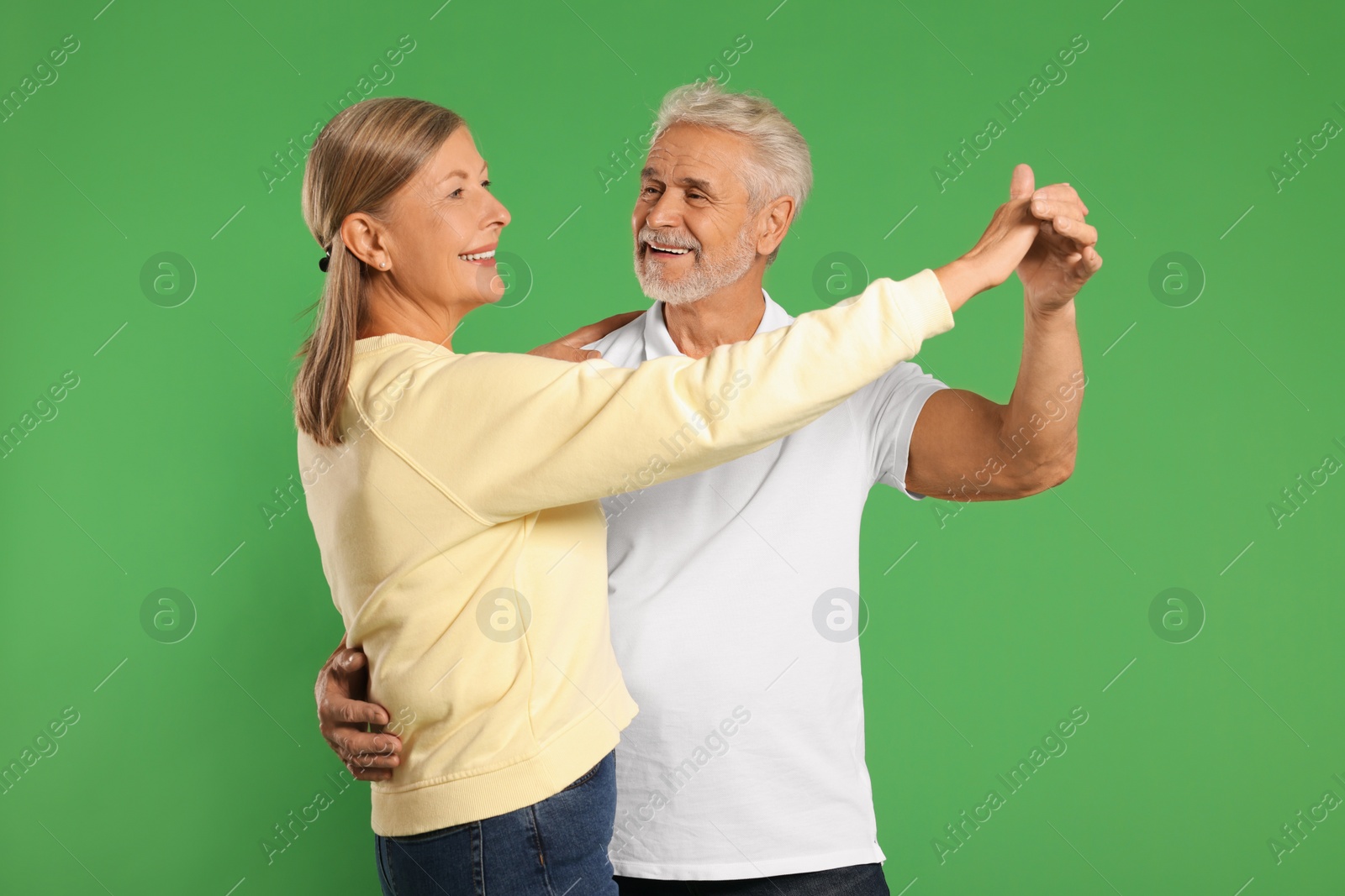 Photo of Senior couple dancing together on green background