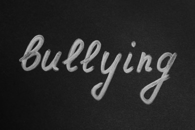 Photo of Word Bullying written on black paper, top view