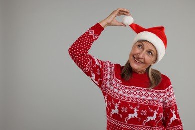Photo of Happy senior woman in Christmas sweater and Santa hat on grey background. Space for text