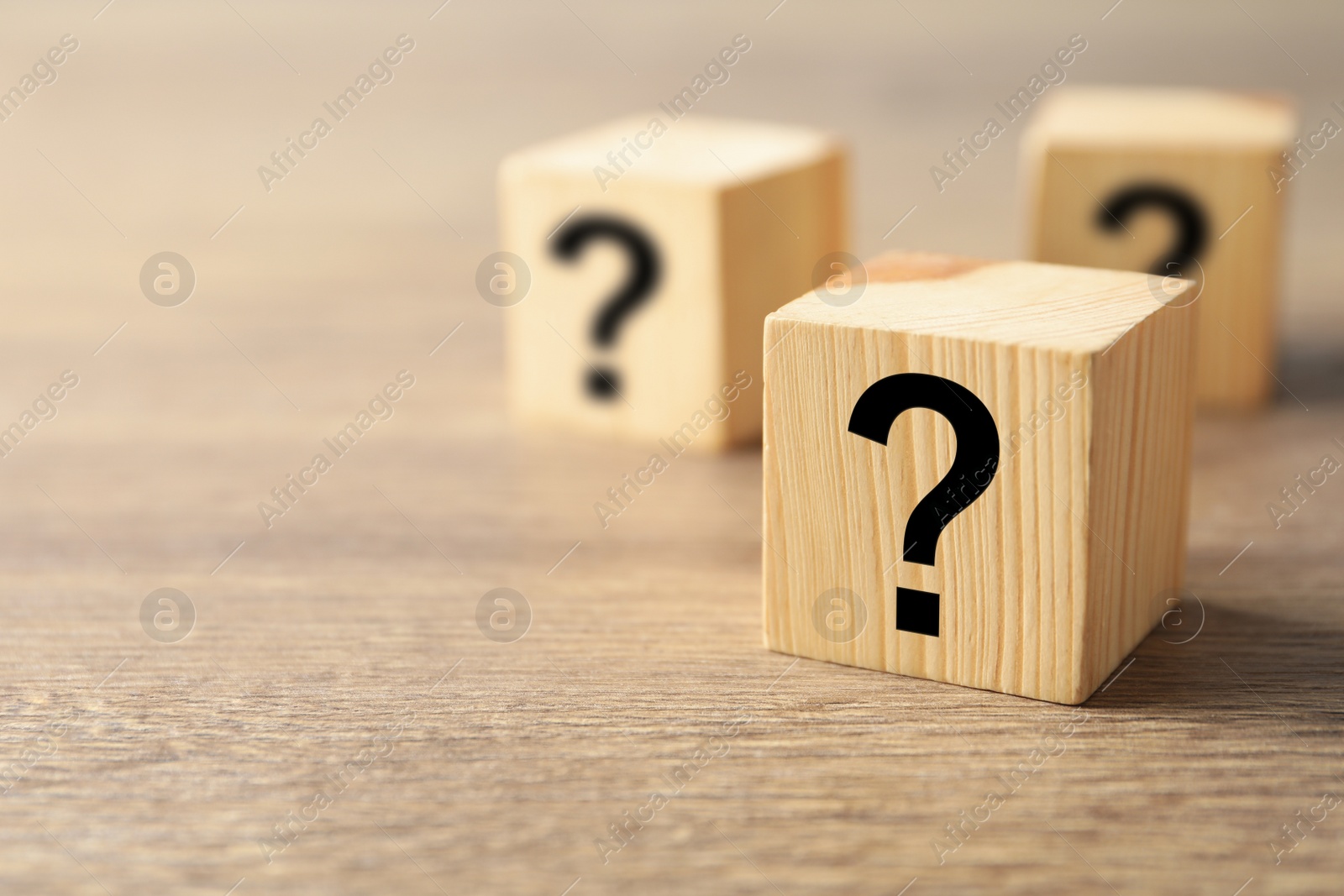 Photo of Cube with question mark on wooden background. Space for text