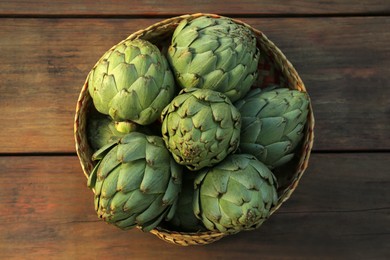 Tasty fresh raw artichokes on wooden table, top view