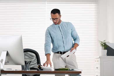 Photo of Young businessman working with documents at wooden table in office