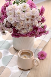 Photo of Cup of hot coffee and beautiful bouquet on wooden table