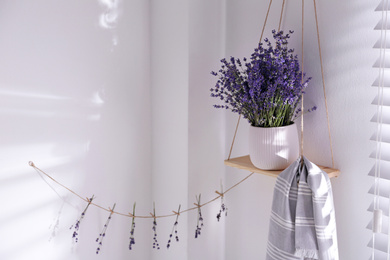 Photo of Beautiful lavender flowers and towel on hanging shelf indoors. Space for text