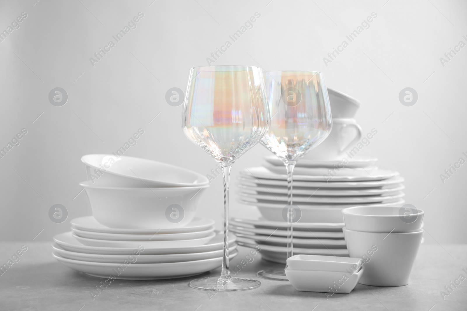 Photo of Set of clean dishes and glasses on light grey table
