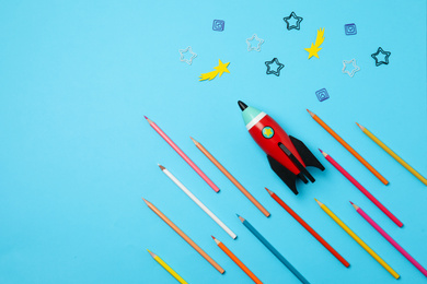 Photo of Bright toy rocket and school supplies on light blue background, flat lay. Space for text