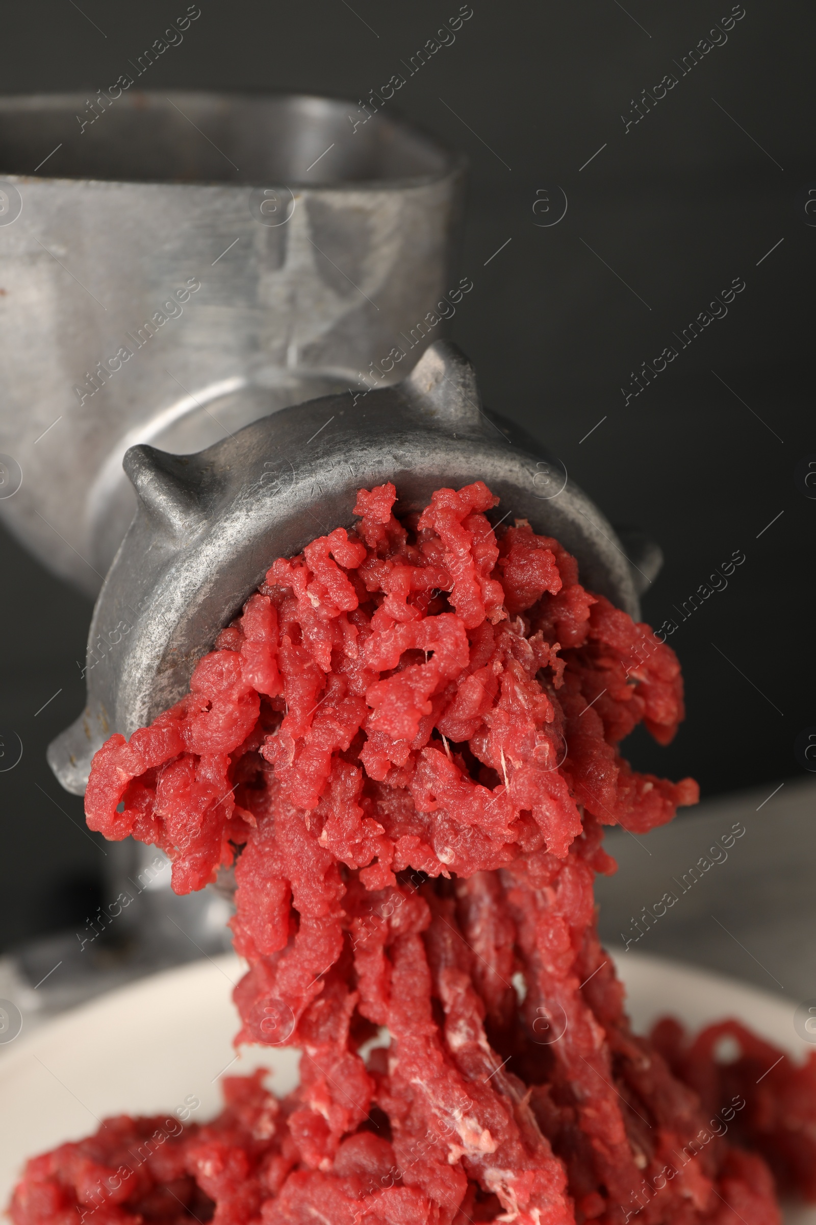 Photo of Metal meat grinder with beef mince against grey background, closeup