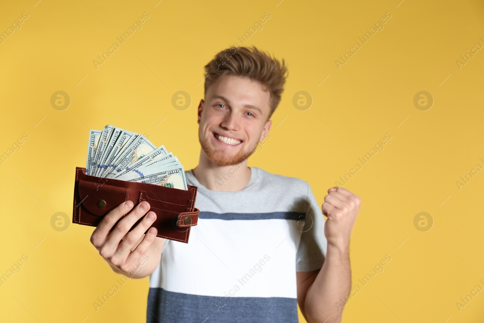 Photo of Young man with money in wallet on color background. Space for text