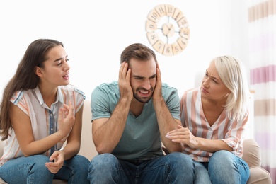 Photo of Young man having argument with wife and mother-in-law at home. Family quarrel