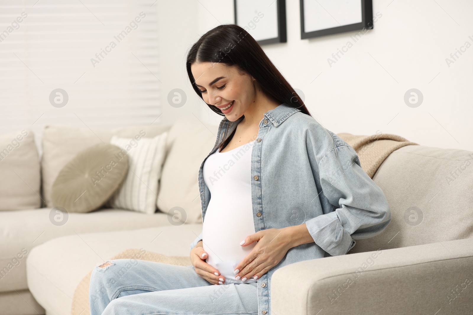 Photo of Happy pregnant woman on sofa at home