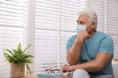 Photo of Senior man in protective mask sitting near window at nursing home