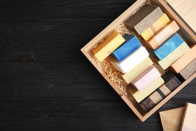 Photo of Many different handmade soap bars in wooden box and space for text on table, top view