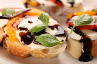 Photo of Delicious bruschettas with mozzarella cheese, tomatoes and balsamic vinegar on beige plate, closeup