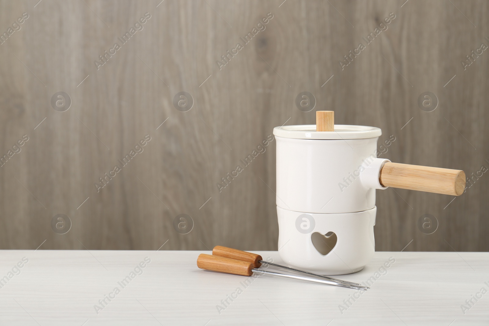 Photo of Fondue set on white wooden table, space for text