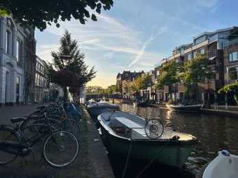 Leiden, Netherlands - August 1, 2022: Picturesque view of city canal with moored boats and parked bicycles