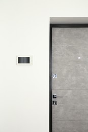 Modern video intercom on white wall near door