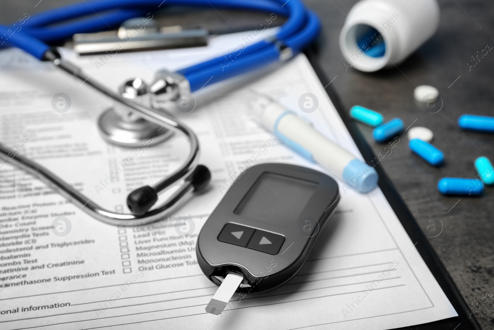 Photo of Composition with form for laboratory test, digital glucometer, medicine and stethoscope on table, closeup. Diabetes concept