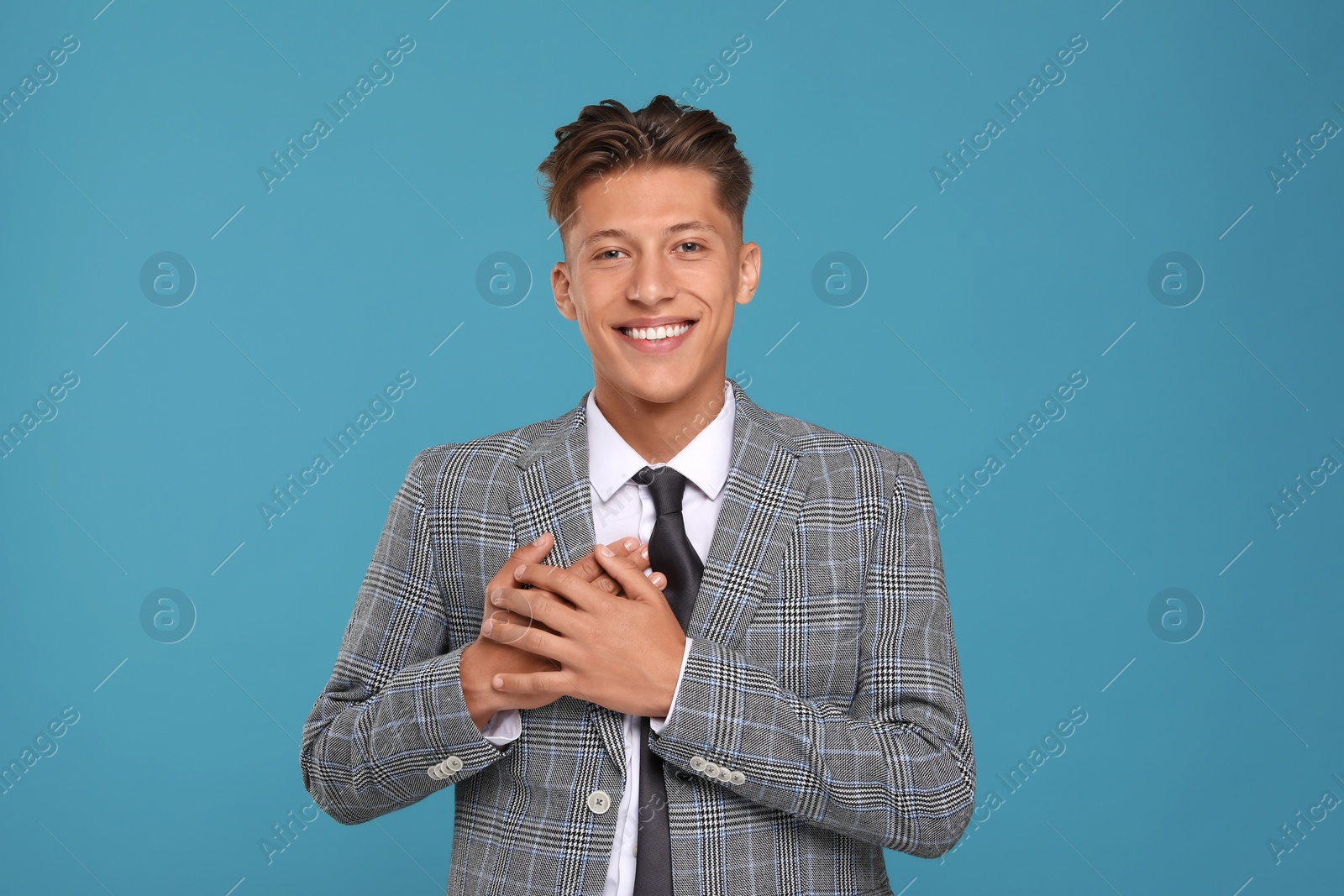 Photo of Thank you gesture. Happy grateful man with hands on chest against light blue background