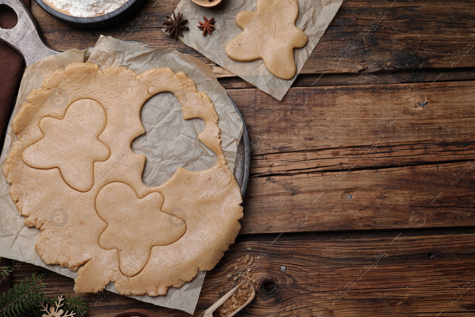 Photo of Flat lay composition with homemade gingerbread man cookies on wooden table, space for text