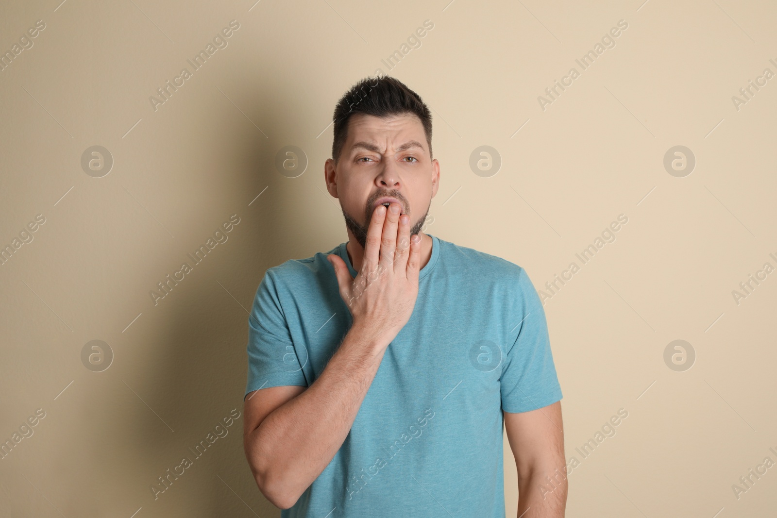 Photo of Portrait of sleepy man yawning on beige background