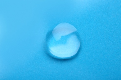 Water drop on color background, top view