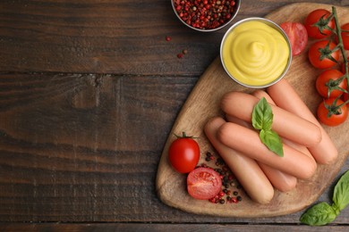 Delicious boiled sausages, sauce, tomatoes and spices on wooden table, flat lay. Space for text