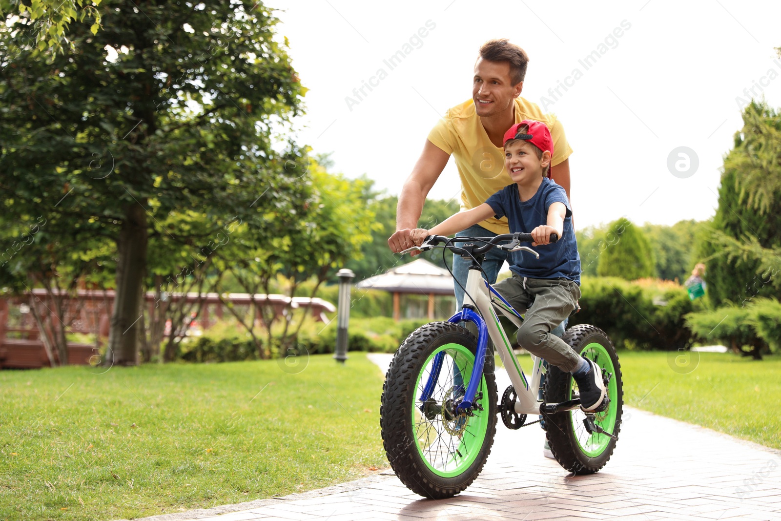 Photo of Dad teaching son to ride bicycle outdoors