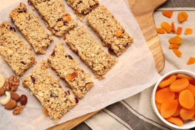 Tasty granola bars, dried apricots and nuts on table, flat lay
