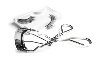 Photo of Curler and false eyelashes on white background